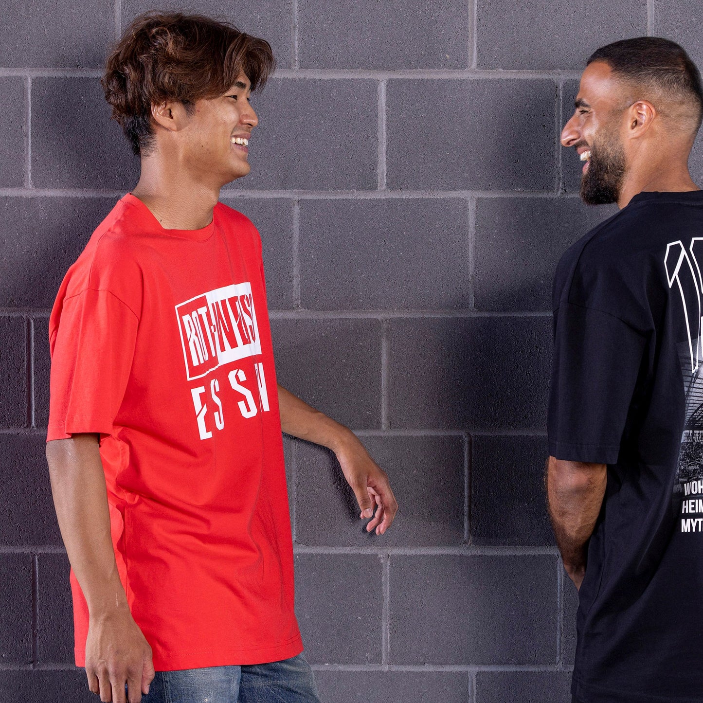 Kaito Mizuta trägt rotes Oversize T-Shirt mit plakativem, weißen "ROT-WEISS ESSEN" Druck frontal auf der Brust