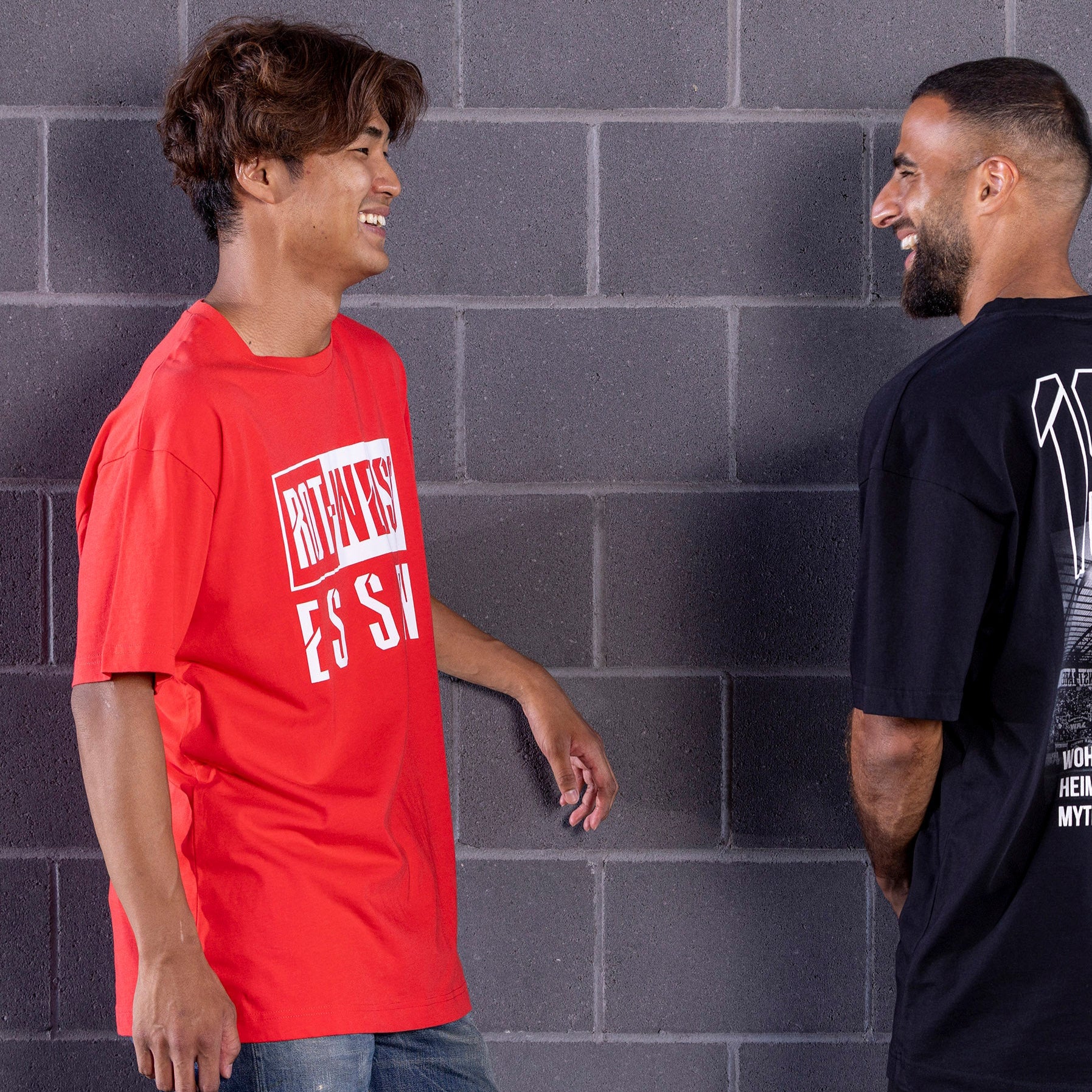 Kaito Mizuta trägt rotes Oversize T-Shirt mit plakativem, weißen "ROT-WEISS ESSEN" Druck frontal auf der Brust